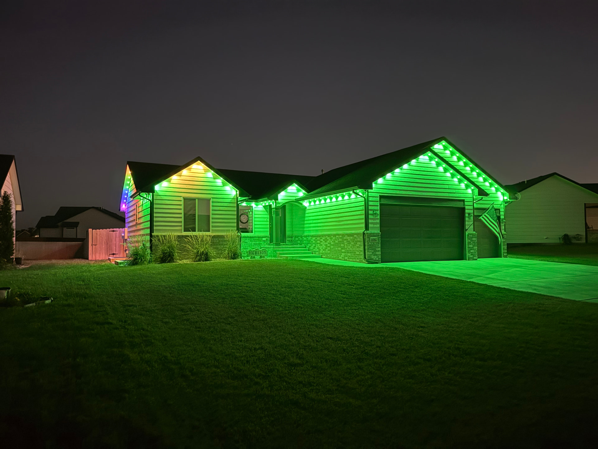 Home outlined in vibrant green permanent LED lights at night