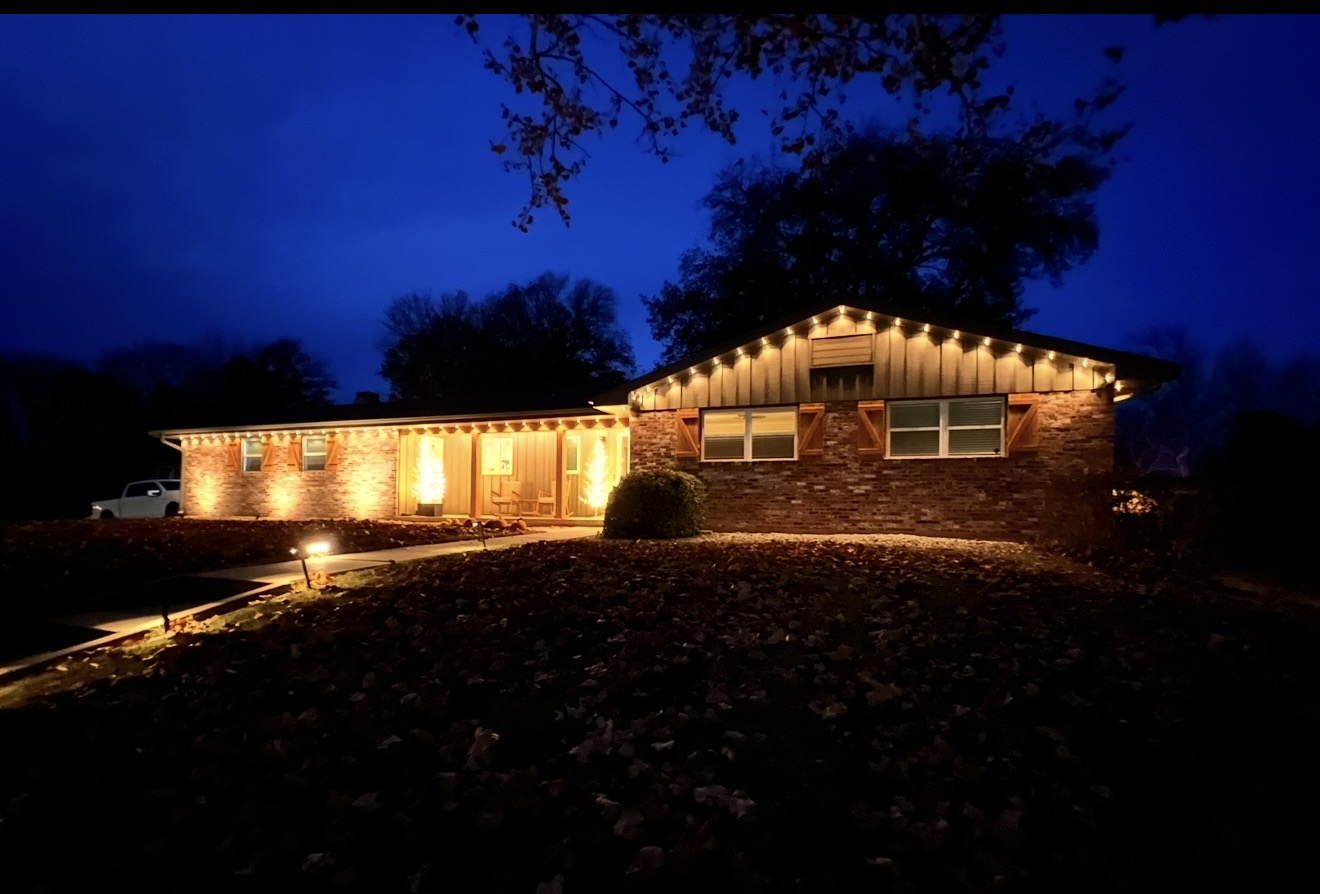 Brick ranch home with warm white permanent LED roofline lighting at blue hour